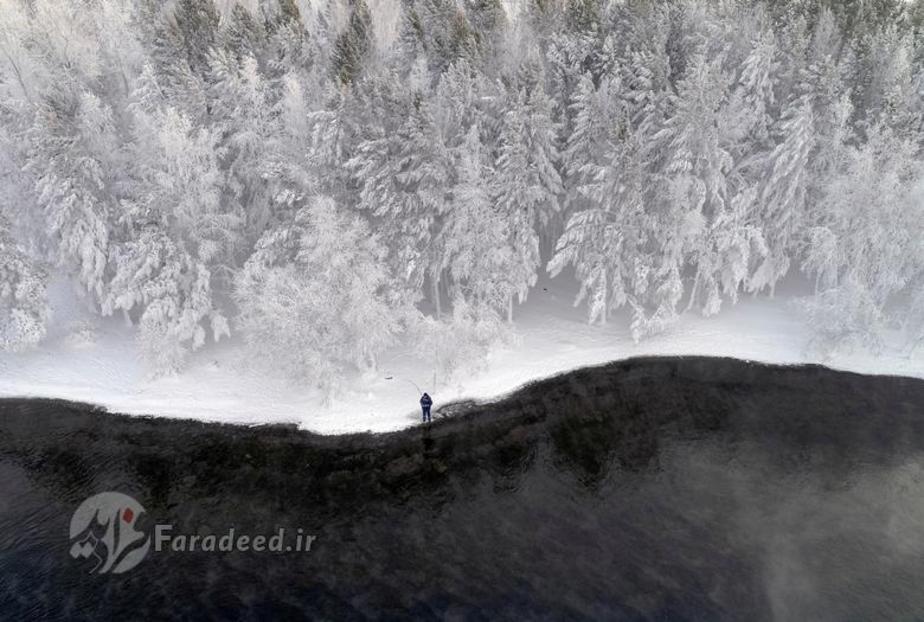 مردی در حاشیه رودخانه ی یی نی سی ای در روسیه ماهیگیری می کند.