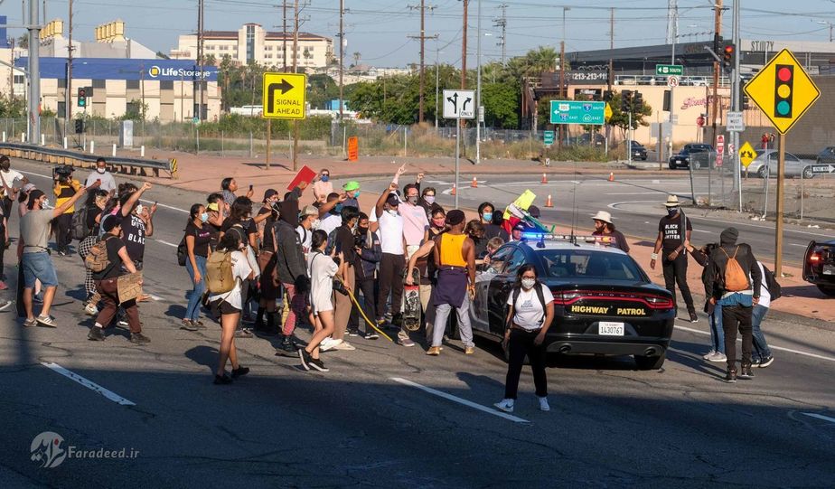 معترضان یک خودروی گشتِ پلیس را در بزرگراه هالیوود از محل دور میکنند. عکاس: Ringo H.W. Chiu/AP