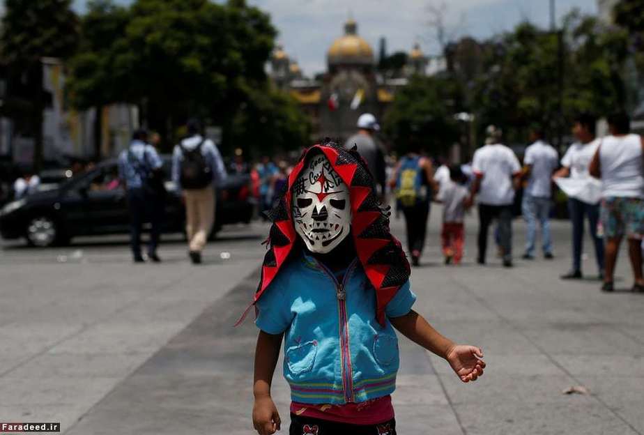 کودکی با ماسک کشتی‌گیر در مراسم سالانه در مکزیکوسیتی